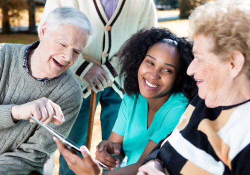 Nurse explaining use of tablet to senior people.